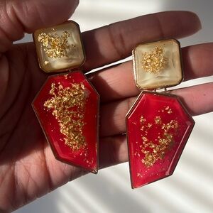 Red drop earring with gold accents.